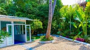 A modern house with glass doors, surrounded by a garden with a gravel path and palm trees. - Sky View Hotel Yangon (Yangon)