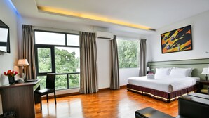 A hotel room with a large bed, a desk with a chair, a desk lamp, and a window with curtains. - Sky View Hotel Yangon (Yangon)