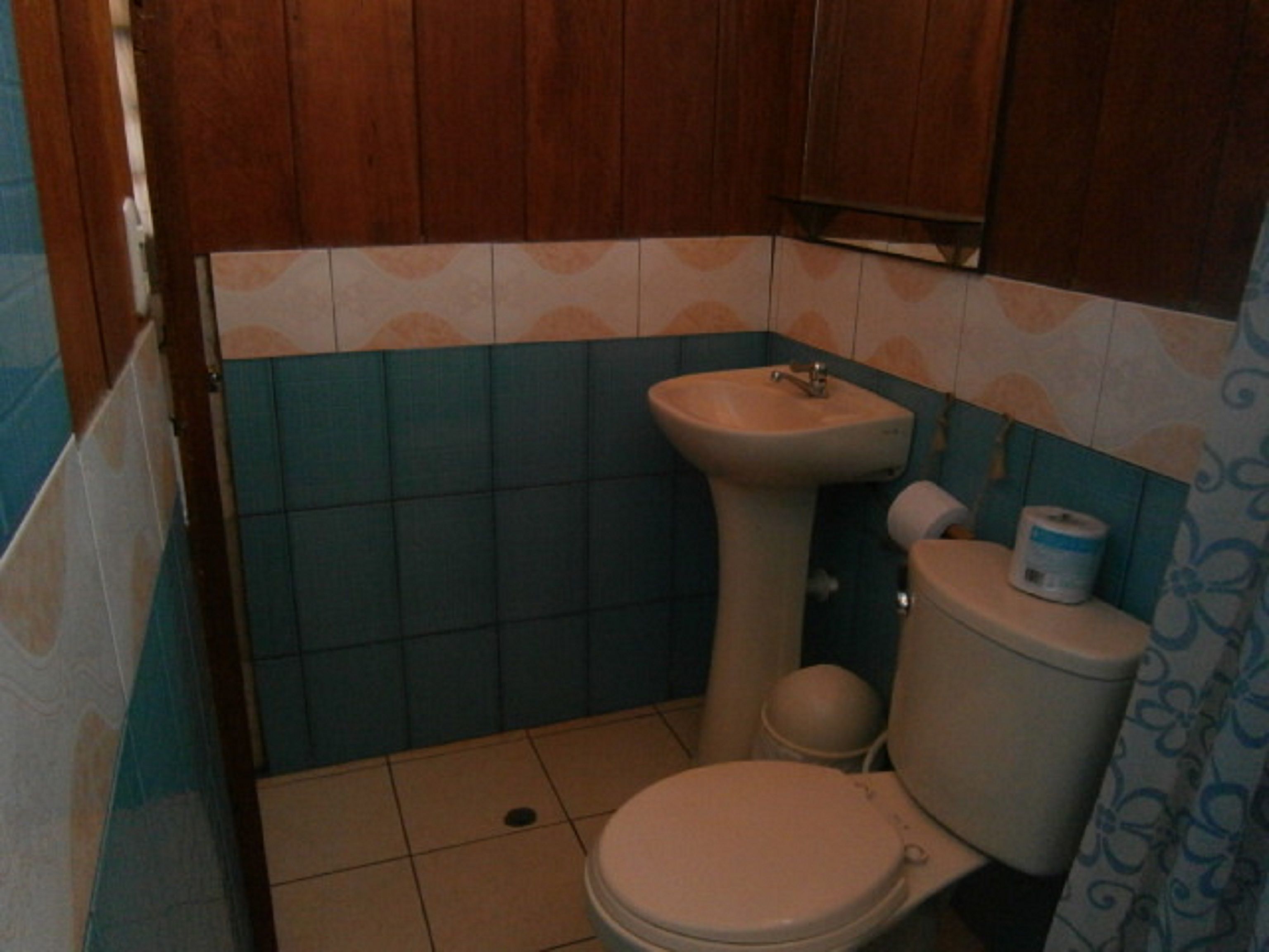 Un baño pequeño con inodoro, lavamanos y paredes de azulejos azules.