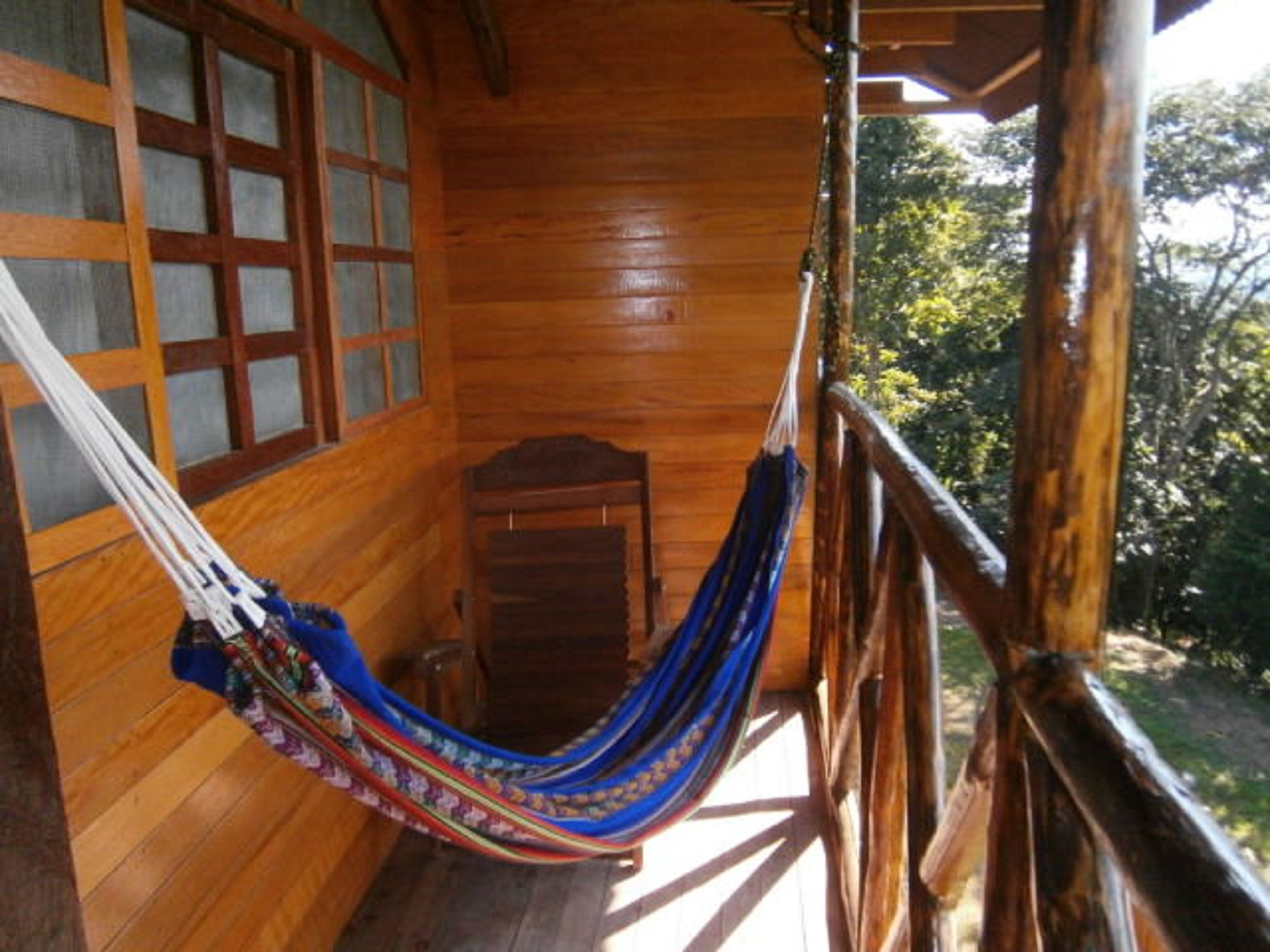 A wooden cabin with a hammock on the porch.