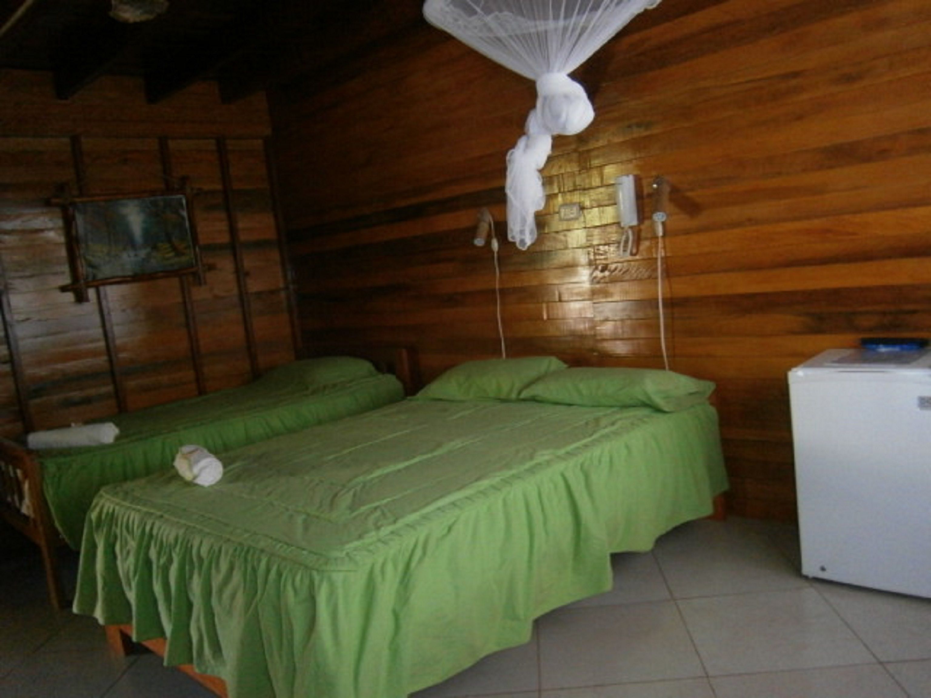 A wooden room with two beds, a small table, and a wall-mounted phone.