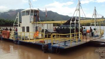 A ferry docked at a river with passengers and vehicles on board.
