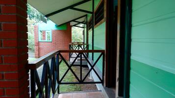 A covered outdoor area with a brick wall, a green building, and a tiled floor.