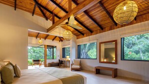 A spacious bedroom with a large bed, a wooden ceiling, and large windows offering a view of the outdoors. - El Remanso Rainforest Lodge (Puerto Jiménez)