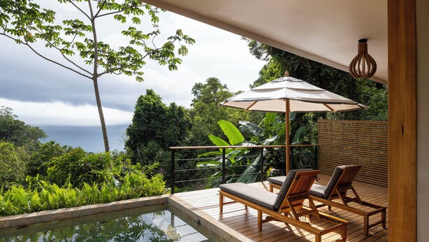 A wooden deck with a pool, lounge chairs, and a view of the ocean. - El Remanso Rainforest Lodge (Puerto Jiménez)