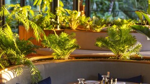 A restaurant with a wooden ceiling, hanging pendant lights, and a dining area with a round table set for two. - El Remanso Rainforest Lodge (Puerto Jiménez)