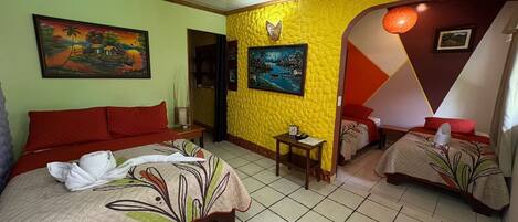 A hotel room with two beds, a small table, and a painting on the wall.