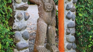 A stone archway with a statue, surrounded by greenery. - Hotel Arte Natura (La Fortuna)