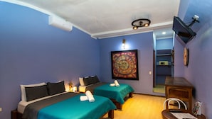 A hotel room with two beds, a TV mounted on the wall, and a wooden table with chairs. - Hotel Arte Natura (La Fortuna)