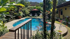 A swimming pool surrounded by lush greenery, with a mountain in the background. - Hotel Arte Natura (La Fortuna)
