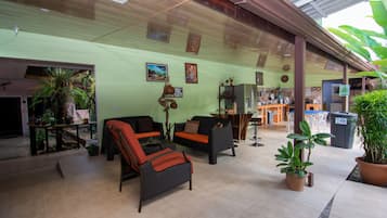 A spacious indoor area with wicker furniture, potted plants, and a tiled floor.