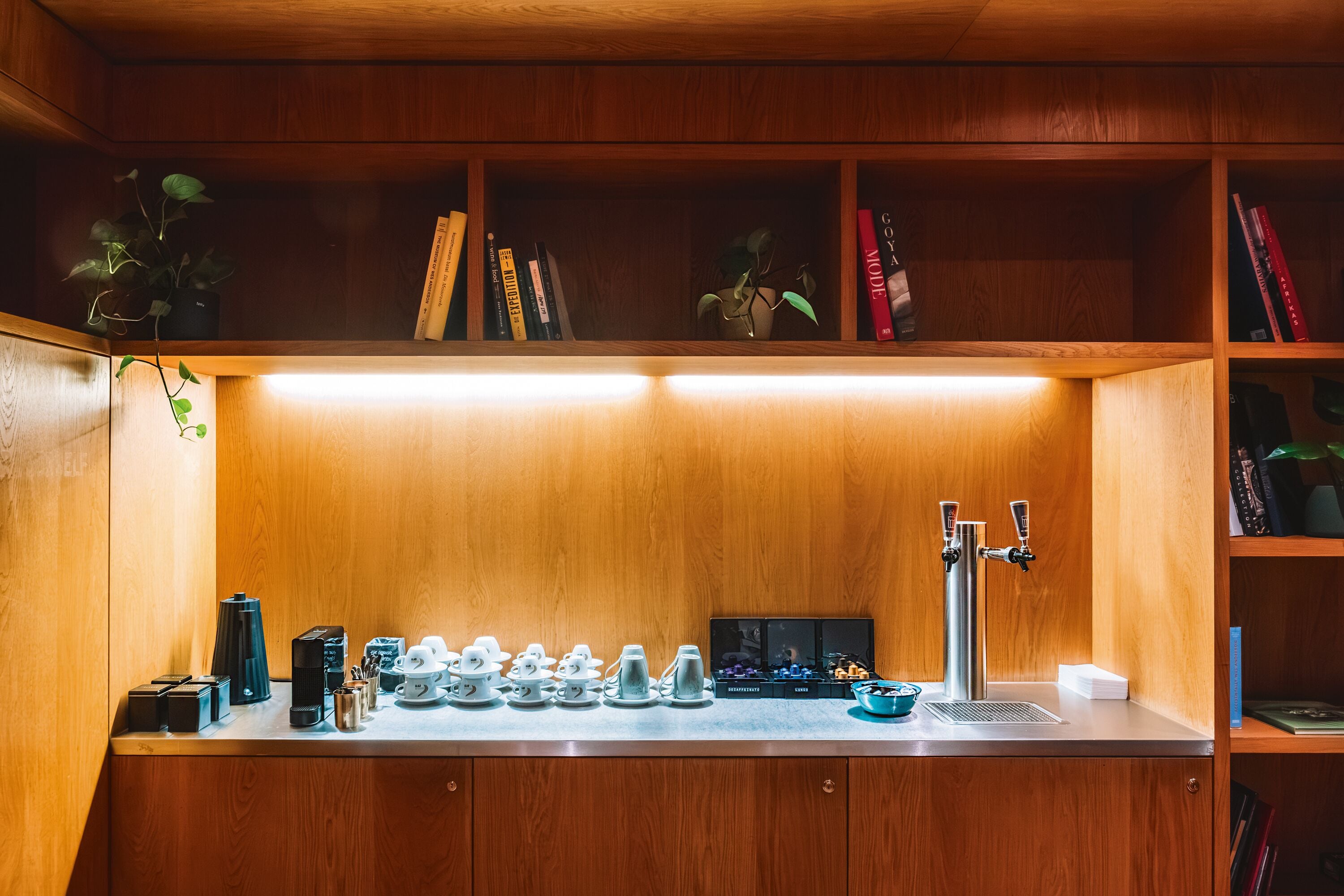 A kitchen with a coffee machine, tea pots, and a sink.