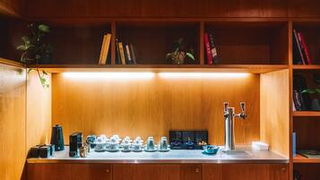 A kitchen with a coffee machine, tea pots, and a sink.