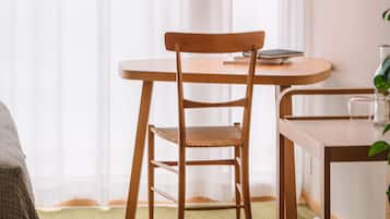 Una habitación con una mesa de comedor de madera, una silla, una lámpara colgante y una planta.