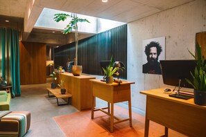 A modern interior with a wooden desk, a computer, a plant, and a large window. - Nomad Design & Lifestyle Hotel - Member of Design Hotels (Basel)