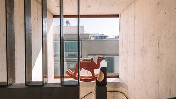 Interior de hormigón con ventana, una escalera y vistas a edificios.