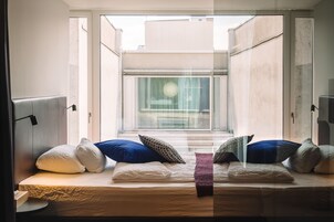 Una cama con almohadas, una mesita de noche y una ventana con vistas al exterior.
