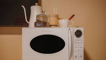 A white microwave oven with a digital display and control panel, placed on a wooden surface.