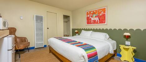 Un dormitorio con cama, una silla, una mesita y una lámpara fijada a la pared.