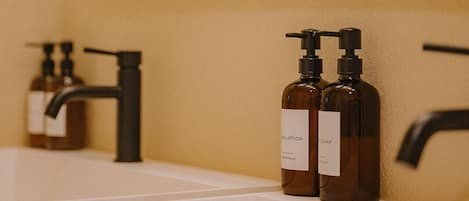 A bathroom with a white sink, two brown soap dispensers, a black faucet, and a mirror above the sink.