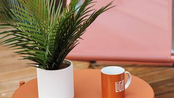 Una mesa pequeña y redonda con una maceta blanca y una taza anaranjada.