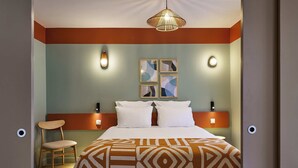 A hotel room with a bed, a chair, and a wall-mounted light fixture. - Hôtel LIGO by HappyCulture (Marseille)