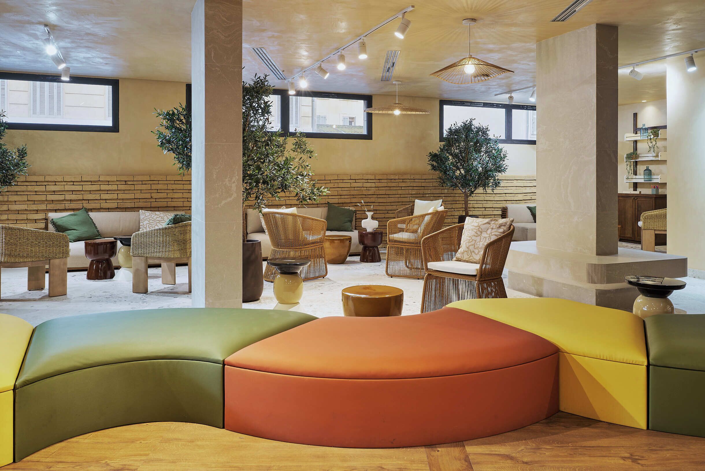 A modern interior with a seating area featuring colorful, curved sofas and wicker chairs.