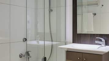 Une salle de bain moderne avec une douche à parois de verre, un lavabo blanc et un meuble-lavabo en bois.
