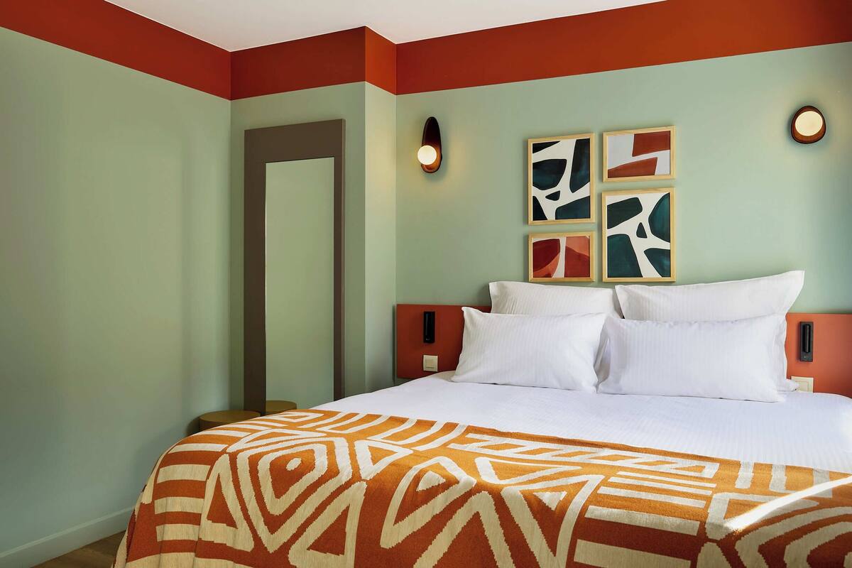 Une chambre d’hôtel avec un lit, une porte et des œuvres d’art accrochées au mur.