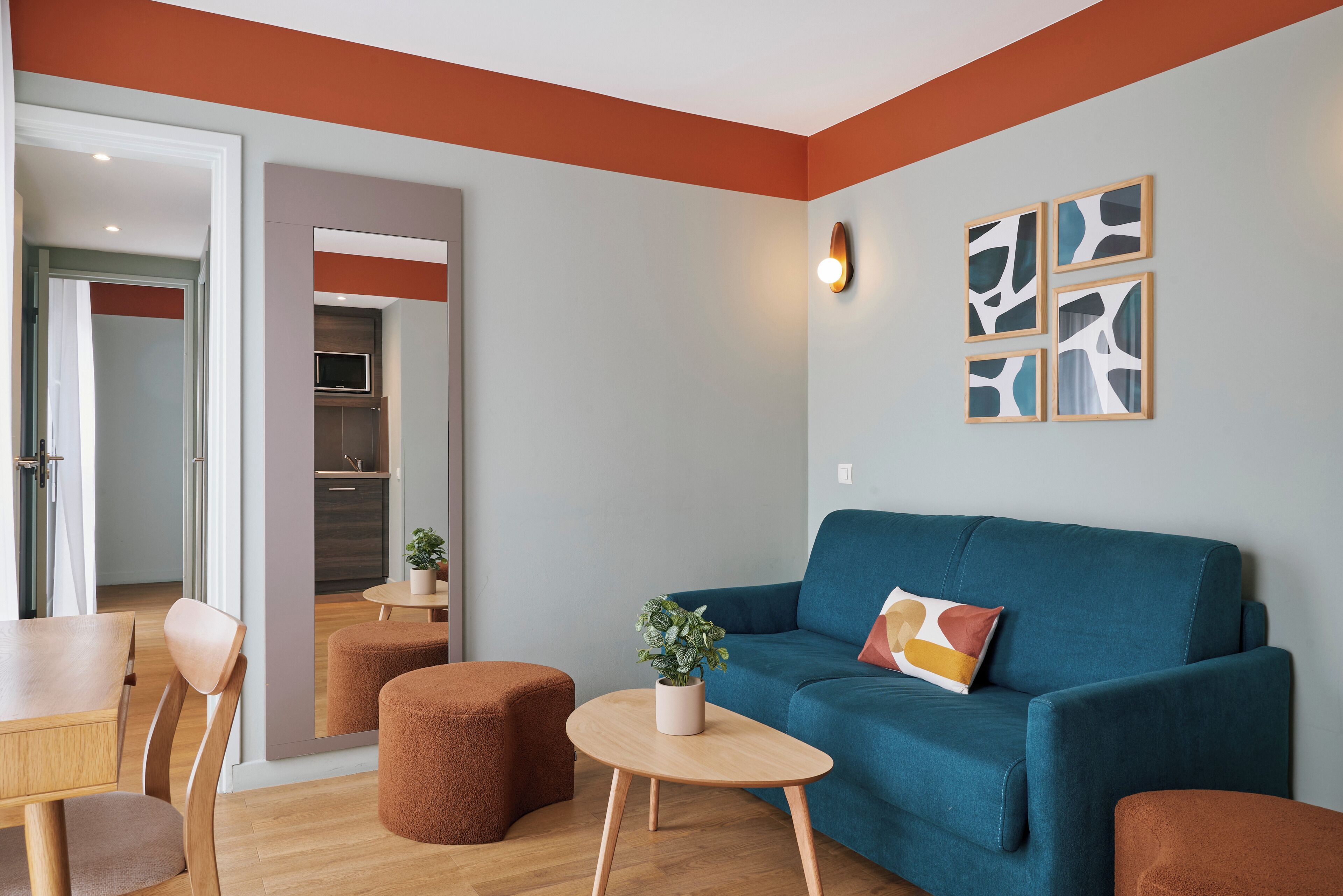 Una sala de estar moderna con un sofá azul, sillas de madera, una mesita y una planta en maceta.