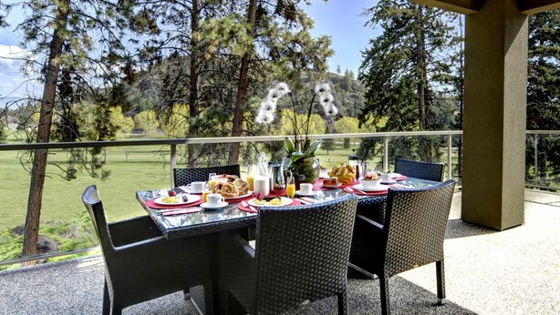 Ein überdachter Essbereich im Freien mit gedecktem Tisch für das Frühstück, mit Blick auf einen Golfplatz.
