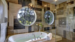 Ein modernes Badezimmer mit einer freistehenden Badewanne, zwei runden Spiegeln und einer Duschkabine.