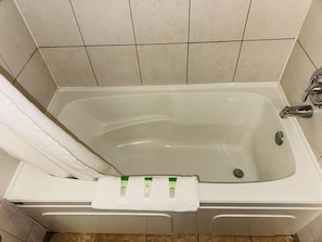 A bathtub with a white towel and two green bottles on it. - Silver Crest Lodge (Grande Prairie)
