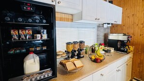 Una cocina con un refrigerador lleno de alimentos, una cafetera y una licuadora sobre la encimera.