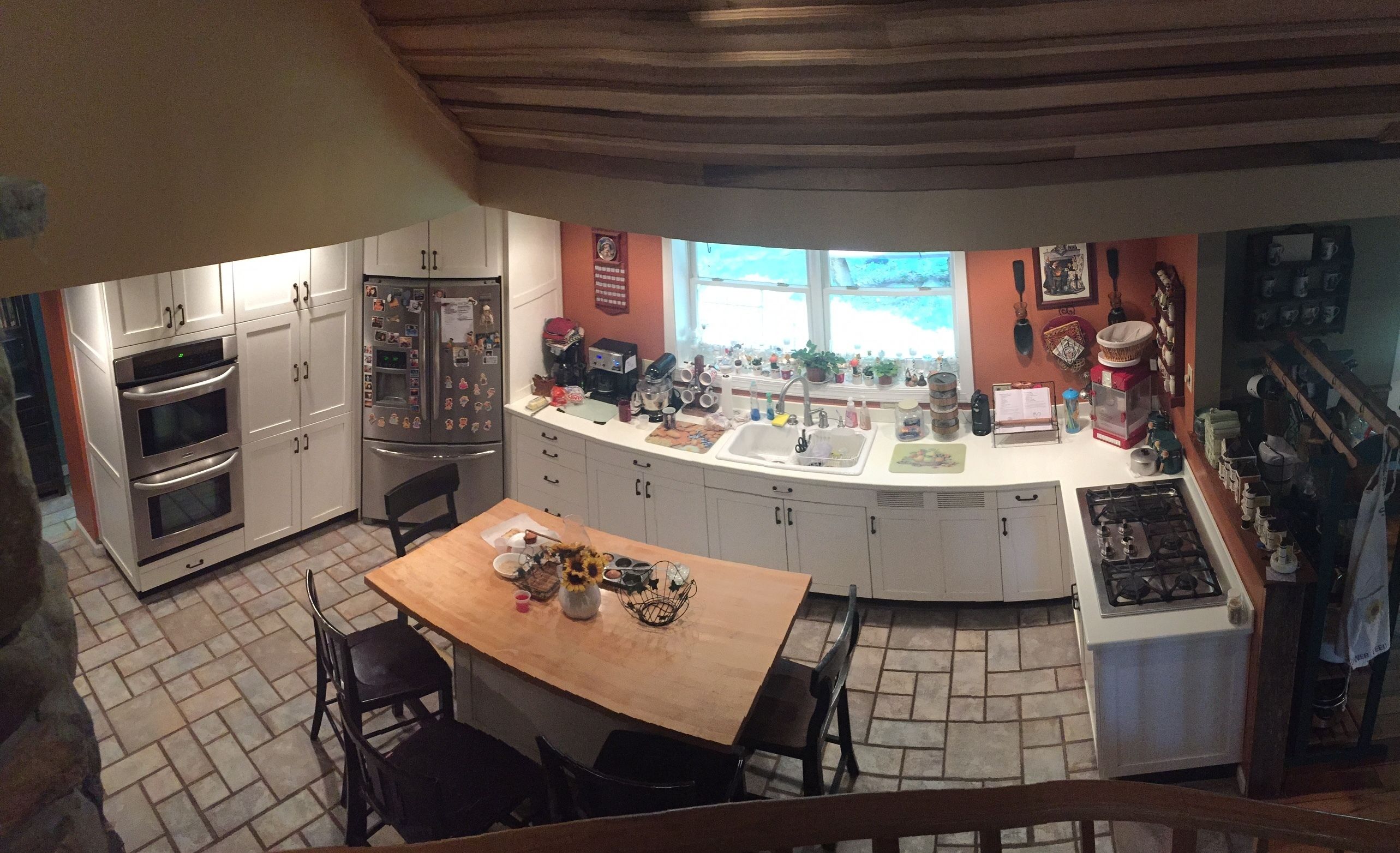 A kitchen with a central island, built-in oven, and a large window.