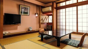 A tatami mat room with a low table, a television, a decorative vase, and a sliding door. - Yanagiso (Toyooka)