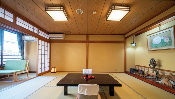 A traditional Japanese room with tatami flooring, a low table with a cushion, a green chair, and a decorative lantern. - Yanagiso (Toyooka)