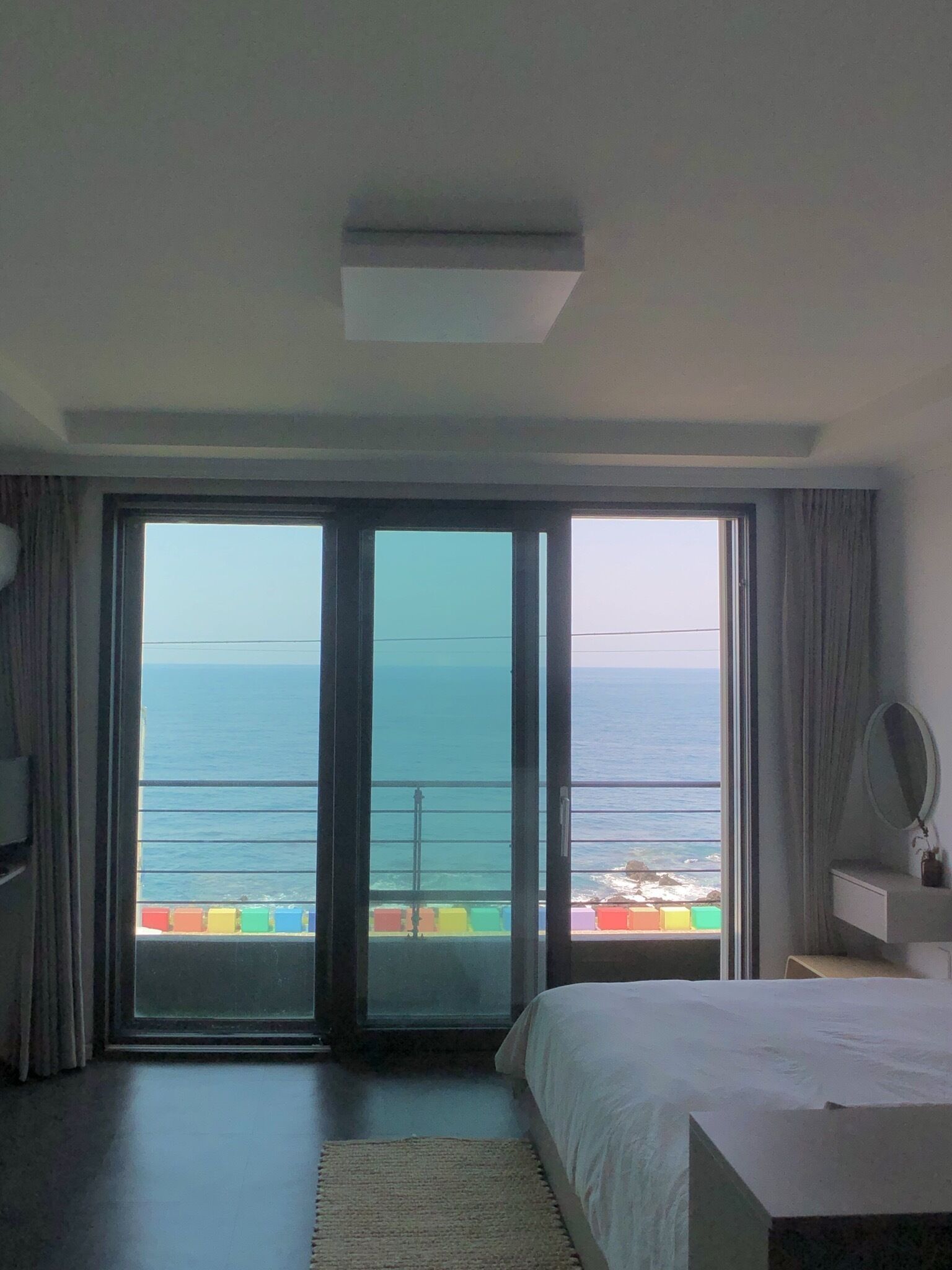 Un dormitorio con un amplio ventanal corredero que da a un balcón con vistas al mar.