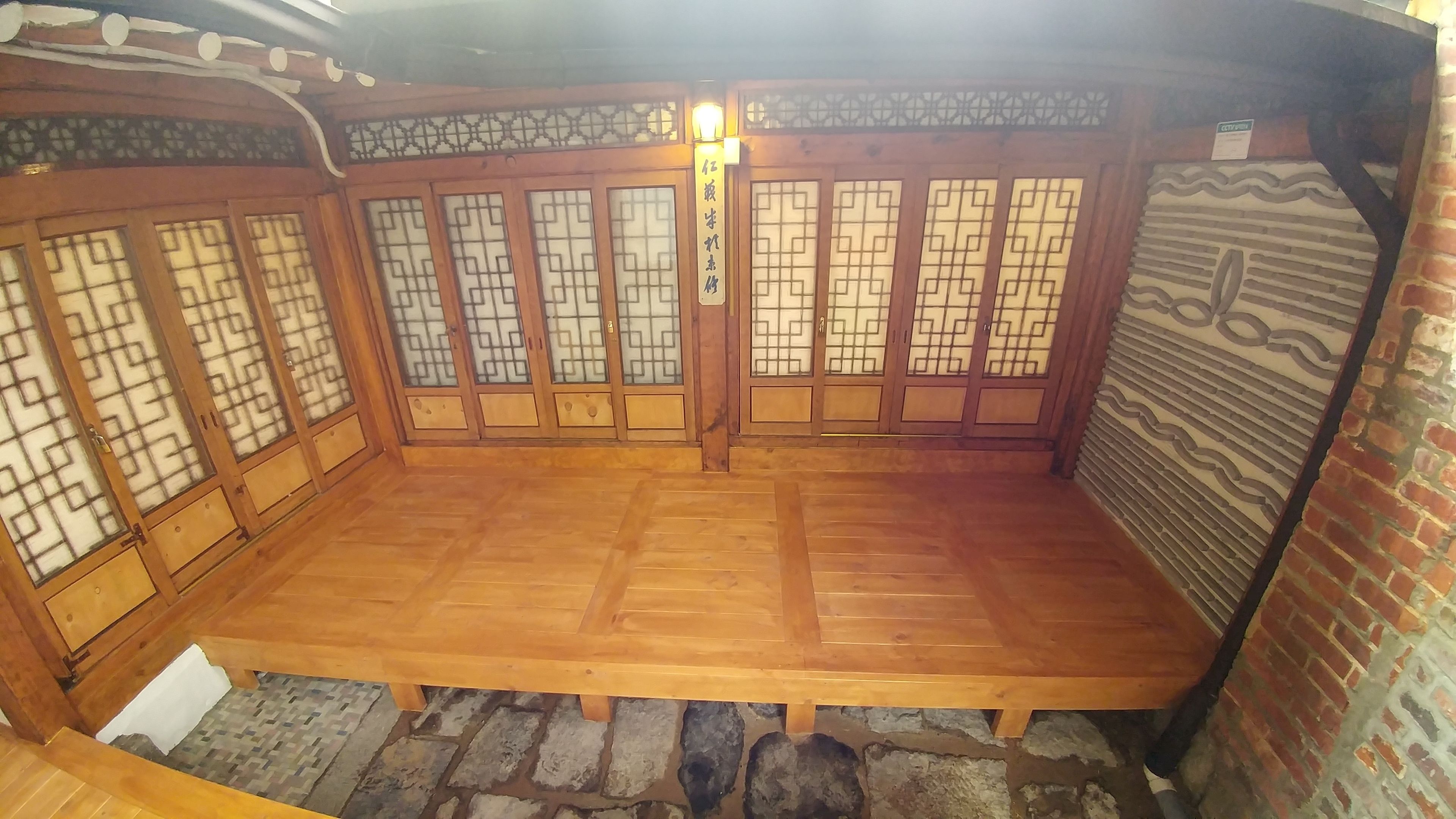 A traditional wooden room with tatami flooring, sliding doors with geometric patterns, and a stone wall.