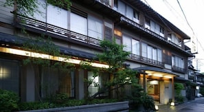 A traditional Japanese building with multiple floors, wooden balconies, and a well-maintained garden area. - Sinonomesou (Toyooka)