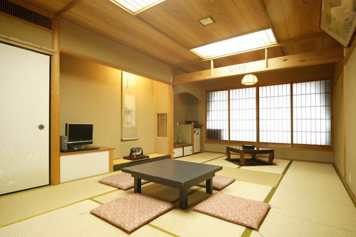 A traditional Japanese room with tatami flooring, a low table, a television, and sliding doors.