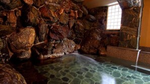 A spa area with a stone wall and a small waterfall. - Sinonomesou (Toyooka)