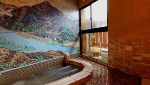 A hot tub with mosaic artwork on the wall, a window with a view of a building, and tiled flooring. - Sinonomesou (Toyooka)
