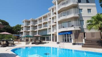 Relax by the pool at LITIMAX RESORT, where a lounge chair and umbrella await.