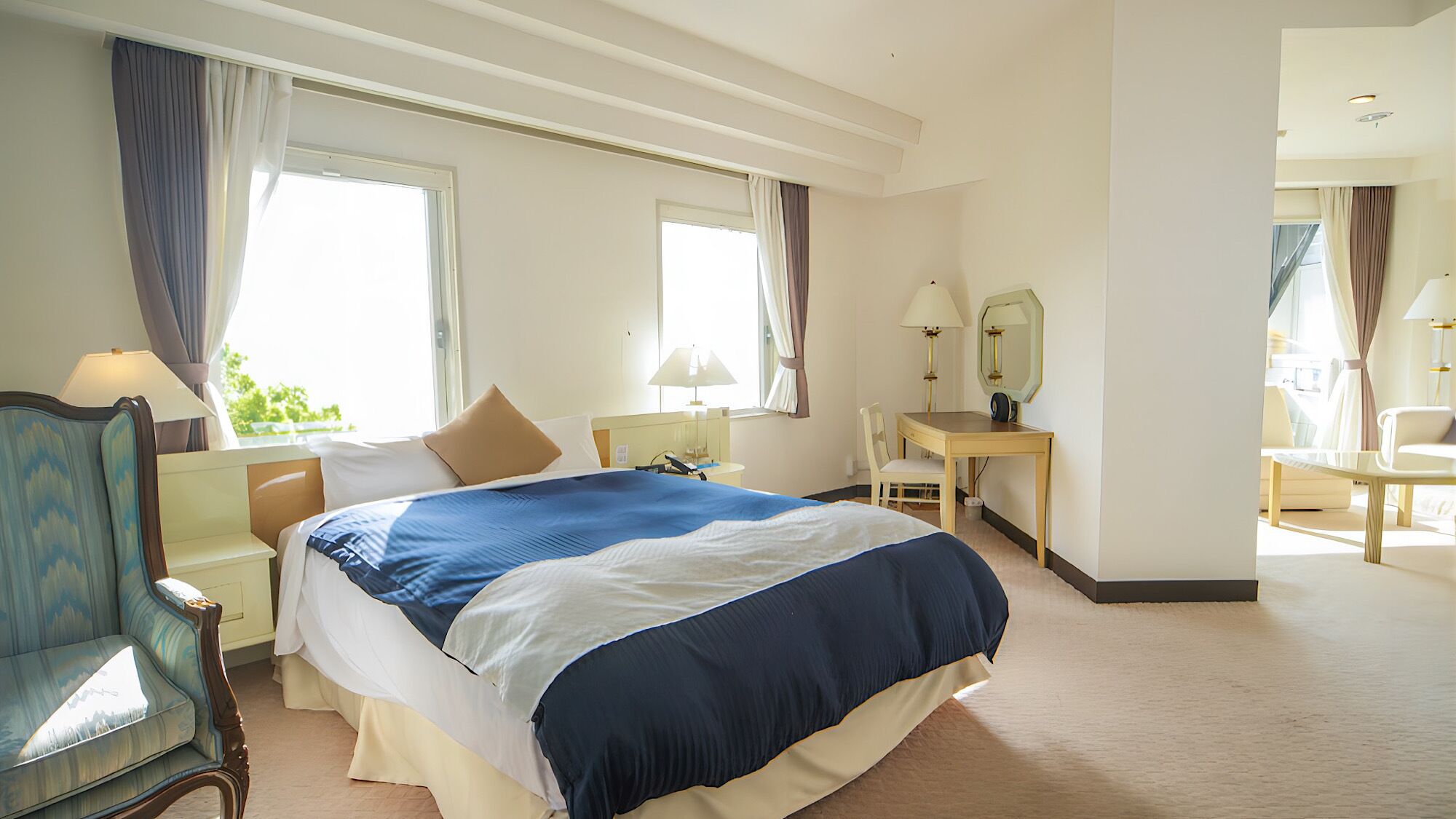 Een hotelkamer met een groot bed, een bureau, een stoel en een spiegel.