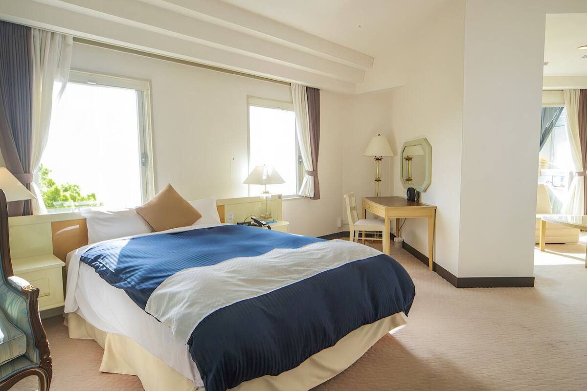 Une chambre d’hôtel avec un grand lit, un bureau, une chaise et un miroir.