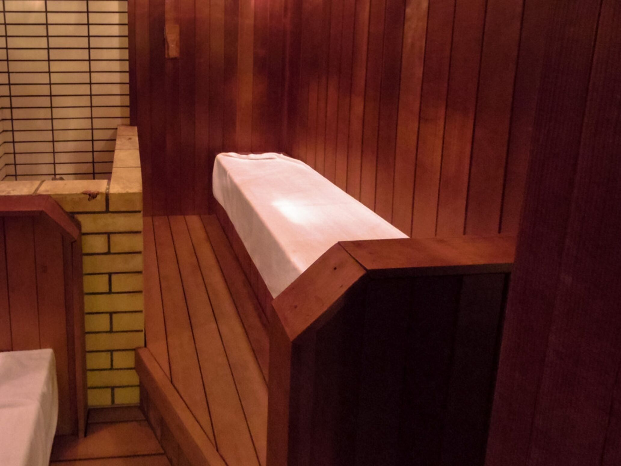 A sauna with wooden benches and a tiled wall.