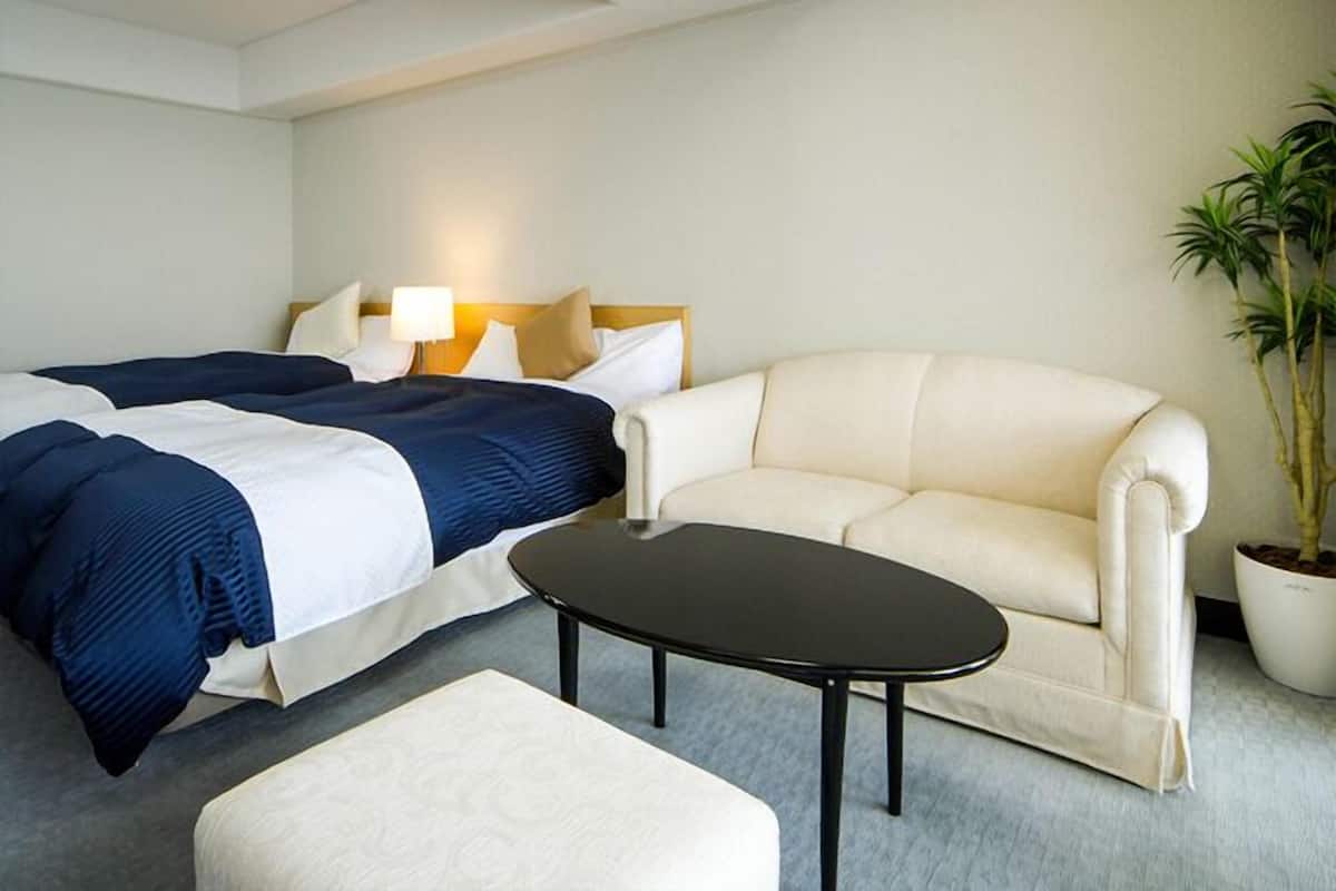 A hotel room with a bed, a sofa, a coffee table, and a potted plant.