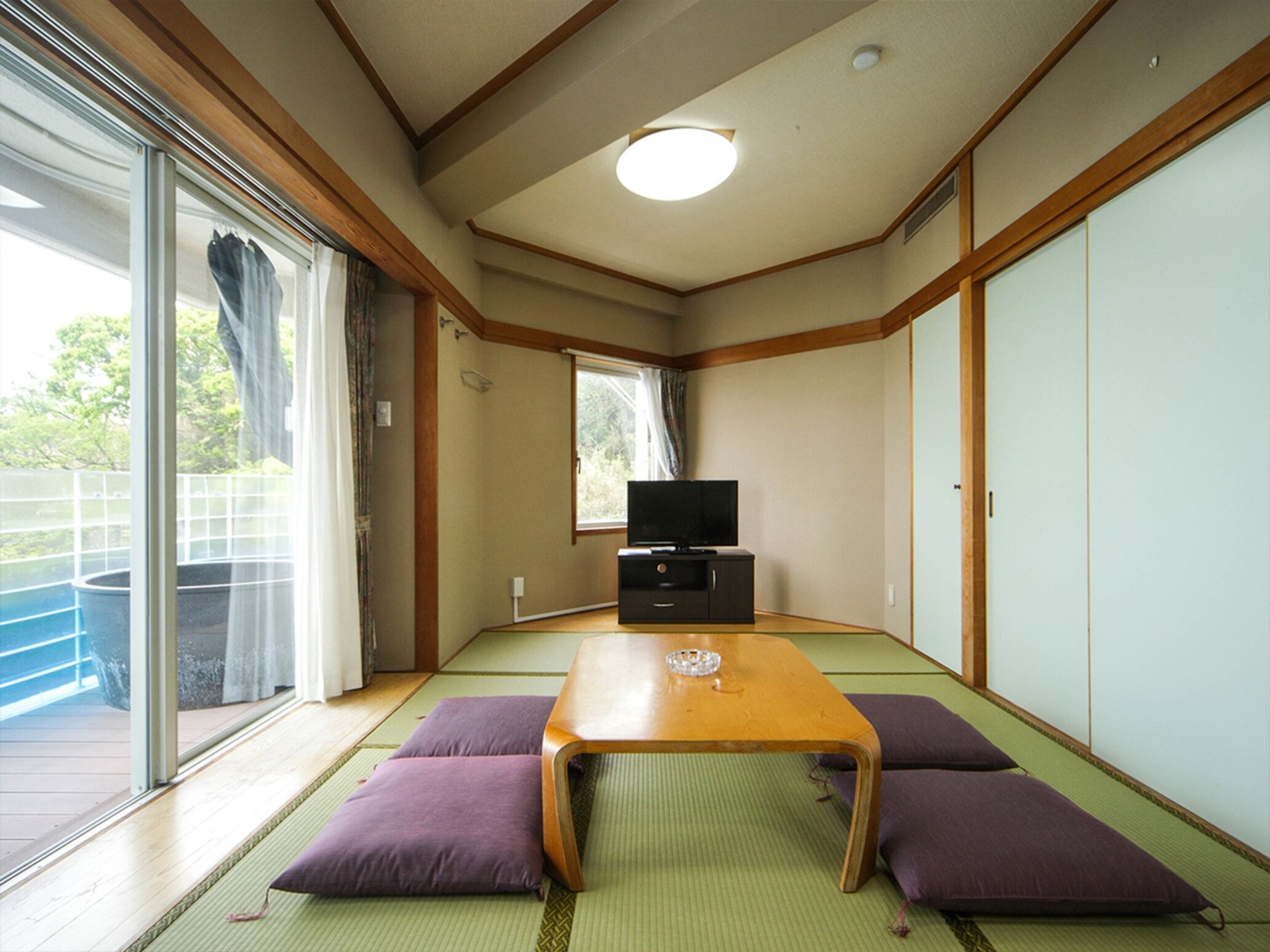 Een traditionele Japanse kamer met tatami vloerbedekking, een lage houten tafel en paarse kussens.