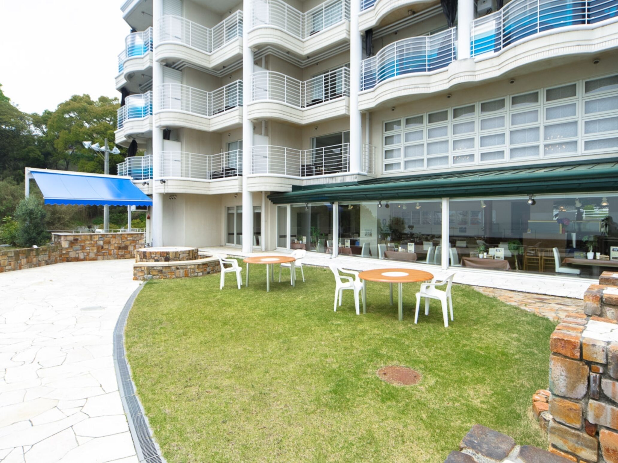 A multi-story hotel with outdoor seating and a stone wall.